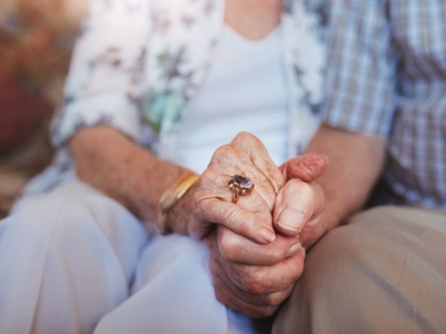 elderly couple holding hands